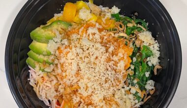 Yummy spicy salmon poke bowl with Kani, mango, avocado, seaweed salad, masago and tempura flakes