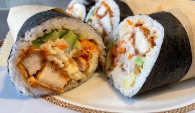 Sushi burrito consisting of panko chicken, imitation crab, cucumber, avocado, and carrot