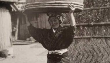 A Japanese woman carrying her children in a bucket on her head, Japan 1900s