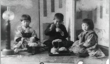 Three children eating noodles. Japan, 1890-1923